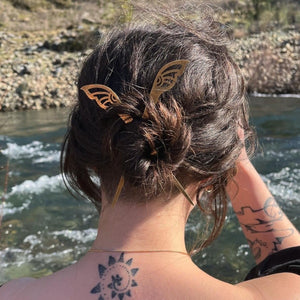 tattooed woman by the rivers edge wearing her hair in a bun with two hair sticksing 