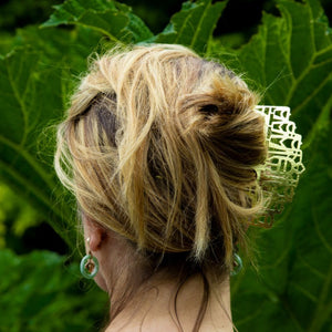 Blond woman facing away with her hair up in a bronze hair comb