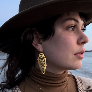 Woman wearing a hat and brass earrings looking to the distance